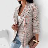 Frau in kariertem Blazer, weißem Top und Jeans. Modetrend, eleganter Look, Business-Casual-Stil, Damenmode, Herbstoutfit.