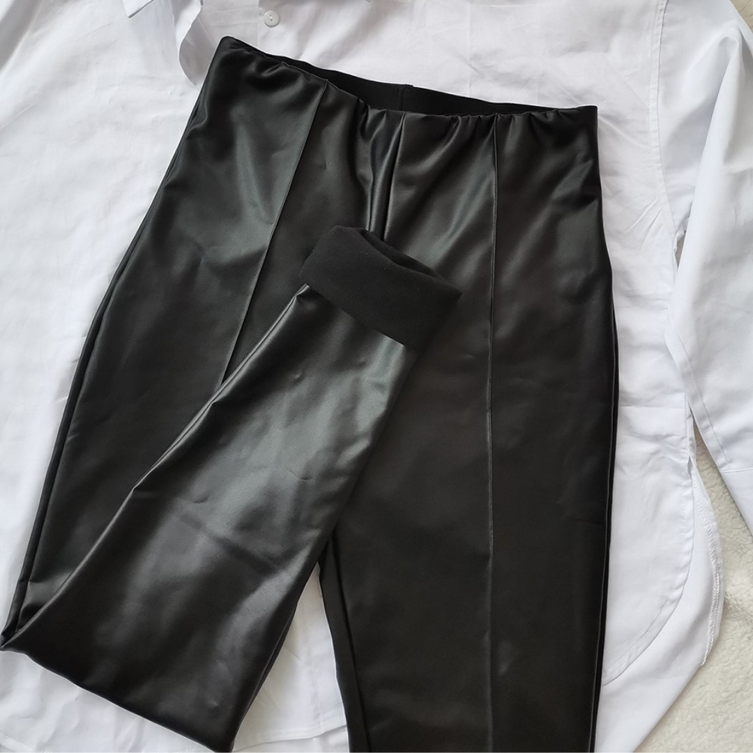 Schwarze Lederhose auf weißem Hemd, modische Damenbekleidung, elegante Kombination, stilvolle Outfits, trendige Modeaccessoires.