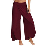 Frau trägt weite, bordeauxrote Haremshose mit asymmetrischem Schnitt. Modische Damenhose, ideal für Sommer und Freizeit.